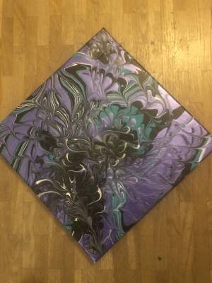 Ein buntes Kissen mit Mustern in violetten und schwarzen Farben.